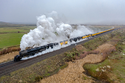 Evanston, WY - May 8, 2019: The Union Pacific Big Boy steam locomotive, wheel arrangement 4-8-8-4, is teamed up with 4-8-4, UP #844, on a double-header steam trip to commemorate the 150th Anniversary of the driving of the Golden Spike.  On a cold, wet and snowy morninging departure from Evanston, WY, the steam locomotives teamed up for one of the steamiest views ever captured!