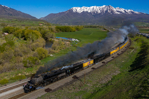 Morgan, UT - May 12, 2019: The Union Pacific Big Boy steam locomotive, wheel arrangement 4-8-8-4, is teamed up with 4-8-4, UP #844, on a double-header steam trip to commemorate the 150th Anniversary of the driving of the Golden Spike.  The duo of powerhouse steam locomotives are heading eastbound from Ogden, UT at Morgan, UT.
