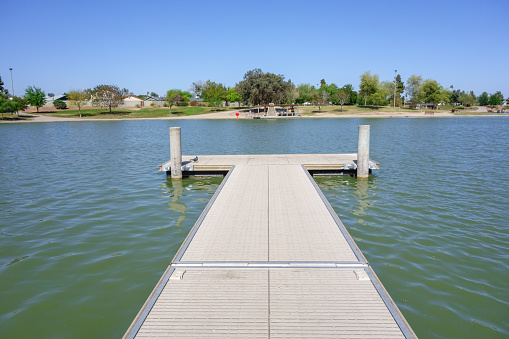 Double sided boat dock stretching into cool spring waters of Kiwanis park lake, Tempe, Arizona
