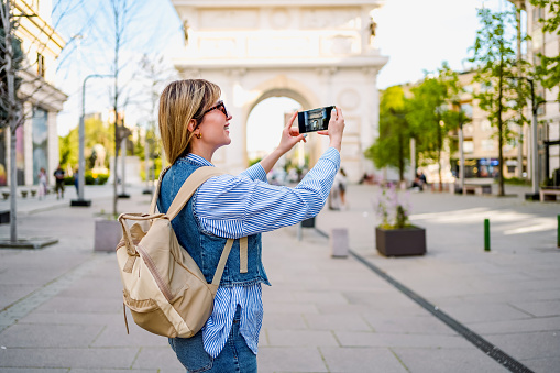 Young tourist woman taking photos in front of triumphal arch in Skopje, North Macedonia