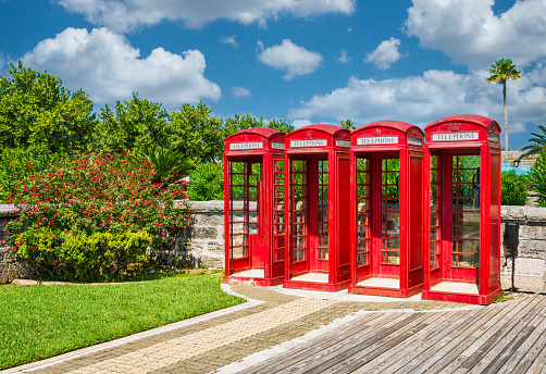 Bermuda - July 19, 2019: 4 red public call box also known as a telephone booth, furnished with a payphone and designed for a telephone user's convenience.