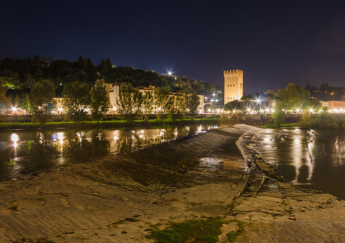 A view of a night city with a medieval tower and the Arno River. Night Florence
