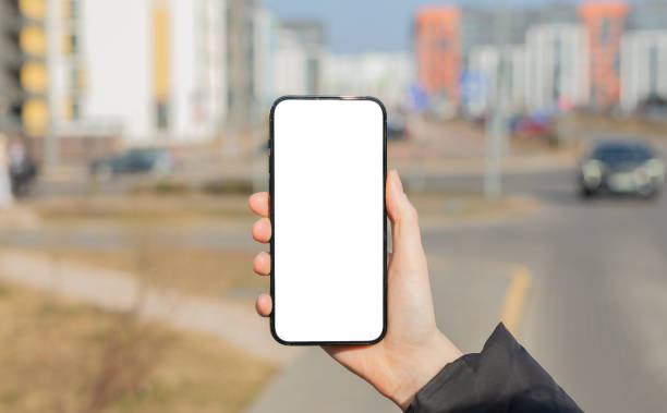 istock Hand holding mobile phone screen, blank smartphone, cellphone mockup, blurred city 2148528247
