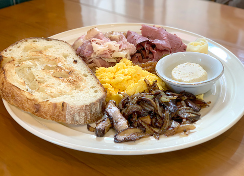 Western typical morning breakfast dish, seen here the toasted garlic bread, grilled mushroom, bacon, and scrambled egg with some tar tar dipping sauce.