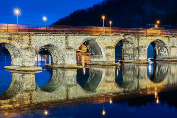 Old stone bridge Ponte Vecchio or Ponte Azzone Visconti at lake Como over the river Adda, reflection in the water. Architecture symmetry.