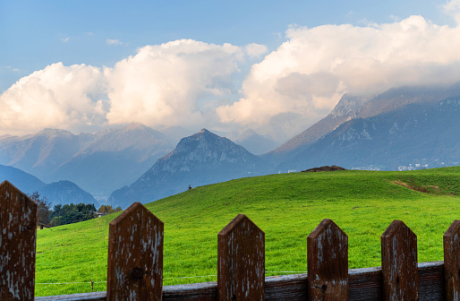 Landscape of the Italian alps in summer, wooden fence in foreground