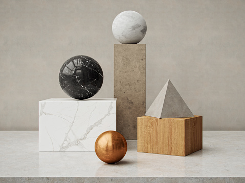 A black marble sphere, a white marble cube, a copper sphere, and a concrete pyramid on a oak wooden block, creating a balanced composition.