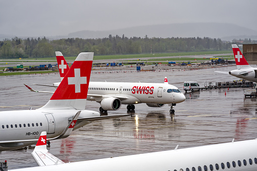 White and red Swiss Airbus airplanes at apron area at Swiss airport Zürich Kloten on a rainy spring evening. Photo taken April 9th, 2024, Kloten, Switzerland.