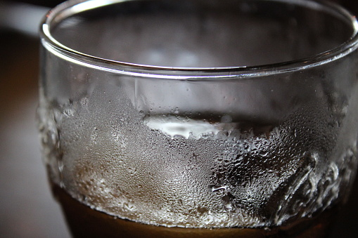 Pint glass filled with cold drink up close, condensation visible on glass