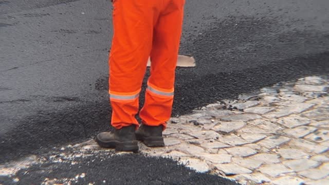 Unidentifiable workers finishing the paving of a street