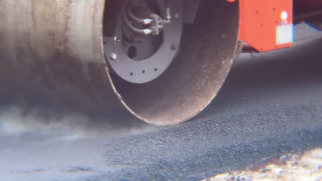 Compressor roller finishing the paving of a street