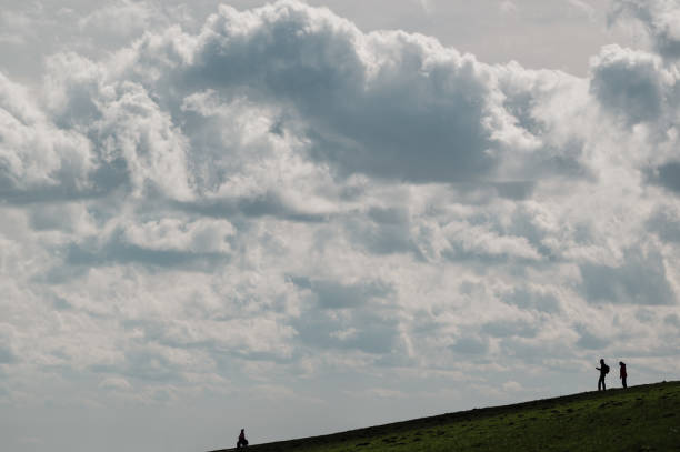 istock Silhouette of people on the dyke with dramatic sky 2148536499