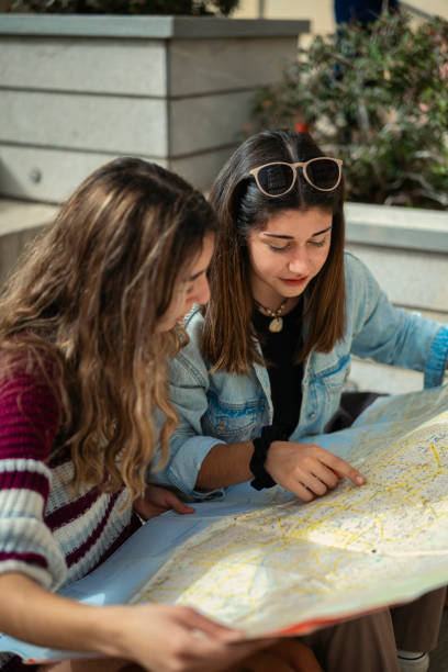 istock Two friends, tourists, sitting on a staircase looking at a map. 2148537143