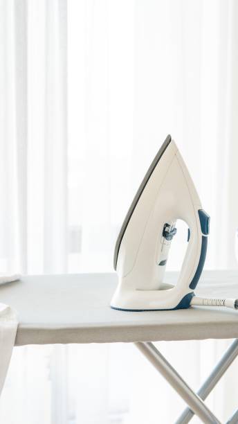 istock Steam iron standing on ironing board near window with copy space 2148538905
