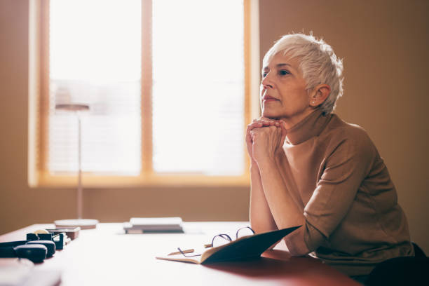 Senior Woman Pondering Over Papers at Home Office