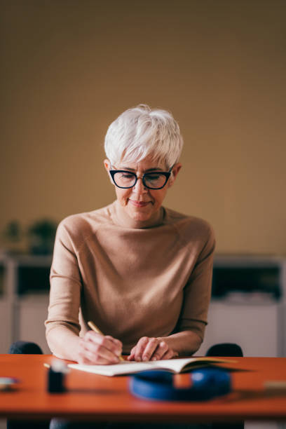 istock Elderly Woman Focused on Writing in Notebook at Home 2148542728