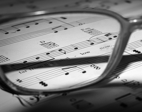 Black n white image through a pair of glasses at a song sheet