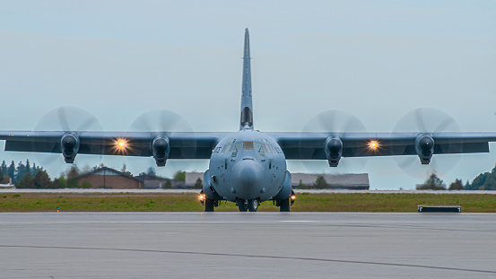 Head-on view of a United States Air Force Lockheed C-130 Hercules cargo plane on a taxiway, with engines running. The C-130 Hercules is a large turboprop cargo plane, first introduced in 1957, and still in use today.