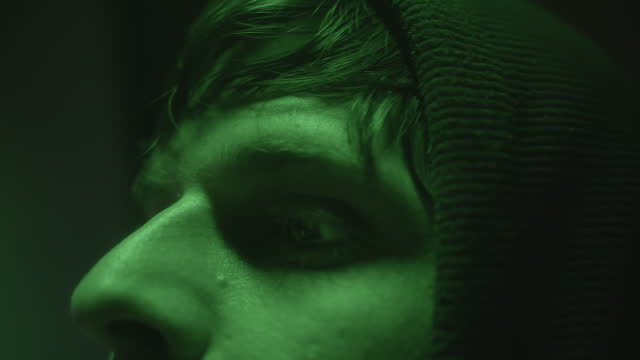 Close-Up Face of Computer Hacker or Programmer at Computer with Green Lights
