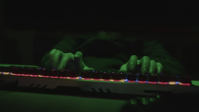 Colorful RGB Keyboard Typing Hacker or Coder Writing Code with Fingers on Green Light