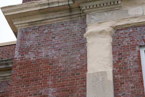 Example of crumbling, deteriorating ornamental precast concrete elements, features, on an old brick school building.