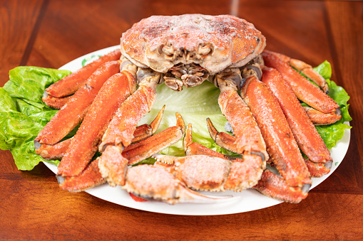 On the plate on the table, there is a large cooked crab