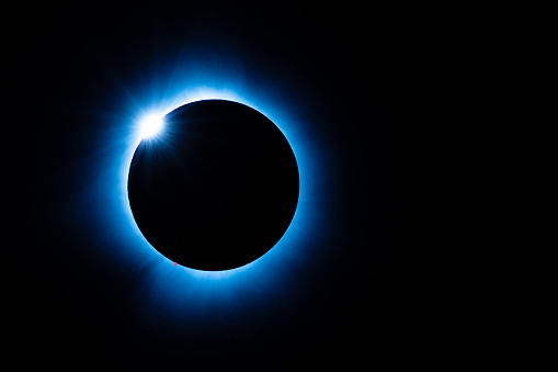 Brillliant Diamond Ring that briefly shines at the onset of phase C2 occuring a few seconds before Totality of the Total Solar Eclipse. Red prominences on the surface of the sun also visible, 2024, Indiana, USA