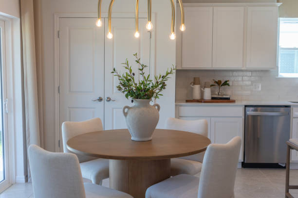 Breakfast nook with round wood table, four upholstered chairs under modern brass chandelier