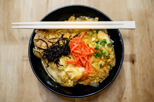 Close-up of Oyakodon, Japanese Chicken and Egg Rice Bowl on wooden table