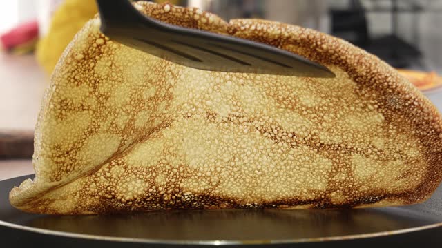 Spatula lifting a pancake, revealing underside texture.