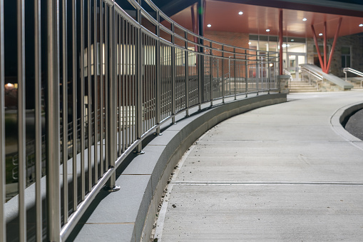 Example of a stainless steel railing along a concrete sidewalk, at the top of retaining wall.