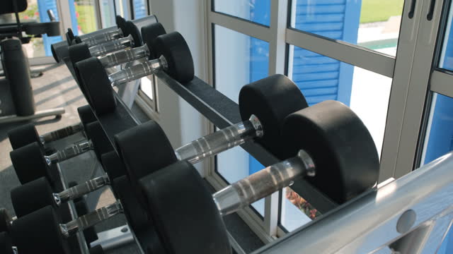 Woman taking dumbbells from the rack in a gym