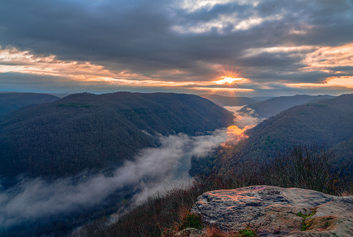 Capture the magic of dawn at Grand View, New River Gorge National Park, West Virginia. Witness the sky ablaze with color as the sun peeks over the horizon, casting a warm glow on the ancient river and lush Appalachian forest below. This awe-inspiring landscape photograph is perfect for anyone who loves nature, mountains, and breathtaking scenery.