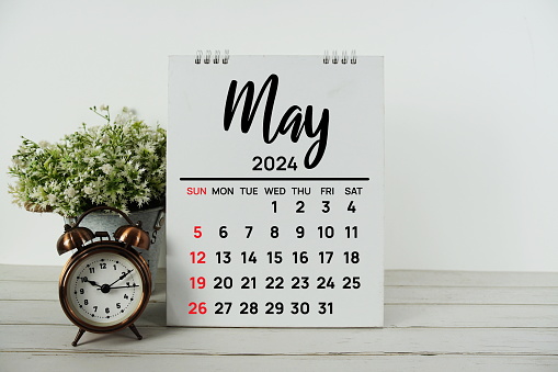 May 2024 monthly calendar with vintage alarm clock on wooden background