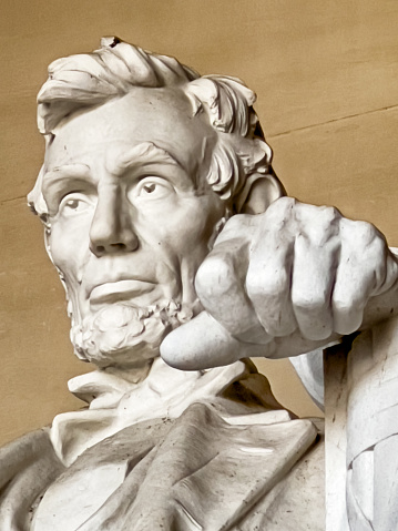 A clenched hand at the Lincoln Memorial shows resolve even as the face calmly looks out over the Mall in Washington DC.