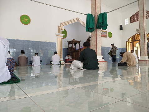 Cilacap, Indonesia - March 29, 2024: Muslim congregation sitting in a mosque preparing to attend Friday prayers in the month of fasting which is very blessed by their god