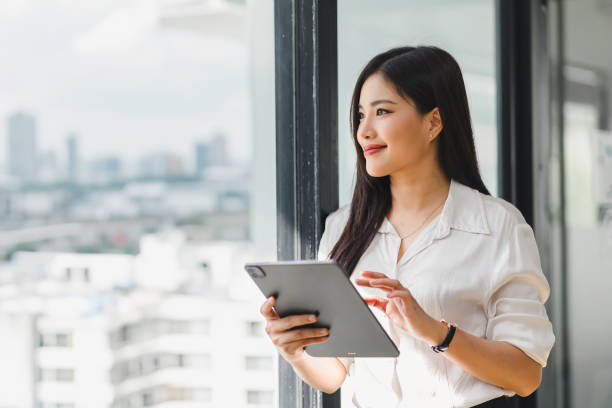 istock Asian professional businesswoman working on a tablet and desktop computer in a corporate office. 2148562541