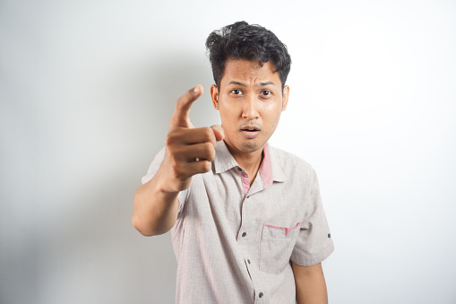 Young asian man wearing shirt standing over isolated white background pointing displeased and frustrated to the camera, angry and furious with you