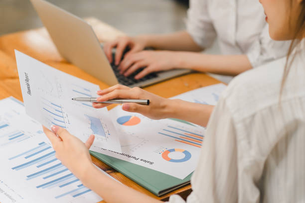 istock Two colleagues analyzing financial data reports on laptop with charts and graphs at modern office. 2148562828