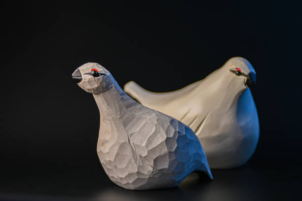 Two white wooden grouse birds on black background.
