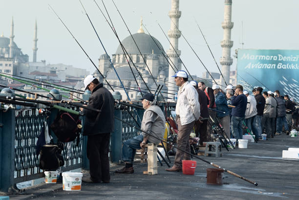 05/02/2016 - Istanbul, Turkey: Busy scene of local fishermen casting lines off Galata Bridge with Istanbul's skyline in the background