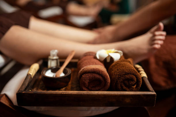 Spa treatment foot massage set with blurred masseuse service foot massage customer on background.
