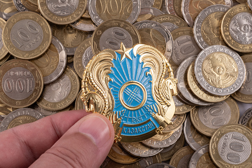 Coat of arms of the Republic of Kazakhstan and coins in denominations of 100 and 200 Kazakhstan tenge