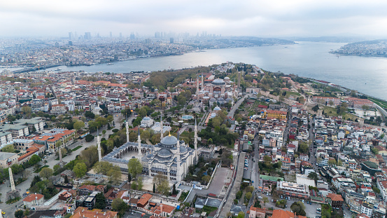 Aerial view of Blue Mosque or Sultan Ahmed Mosque and Hagia Sophia in Istanbul, Turkey. This mosque contains blue paint on the walls and tiles to decorate the interior, and hundreds of stained glass windows with beautiful designs that allow sunlight to creep in during the day and light the interior of the mosque. You can also see The Walled Obelisk or Masonry Obelisk (Turkish: Örme Dikilitaş) in the photo. It is a Roman monument in the form of an obelisk in the former Hippodrome of Constantinople, now Sultanahmet Square in Istanbul, Turkey.