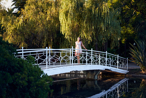 Young woman standing on a white bridge trough the lake