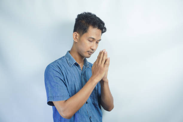 Pray, faith and mockup with a man in studio on a white background asking god for a miracle or help. Trust, religion and spiritual with a handsome young male praying to in belief