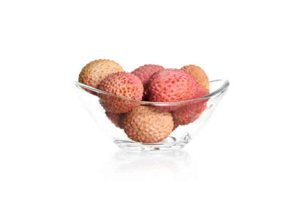 Small ripe tropical lychee berries on a black plate on on the edge of the table, on a black background