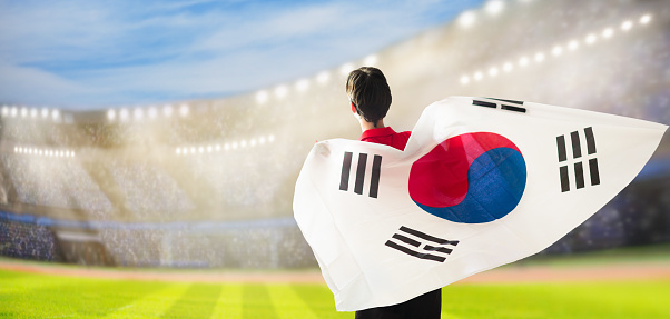 South Korea football supporter on stadium. Korean fans on soccer pitch watching team play. Group of supporters with flag and national jersey cheering for the Republic of Korea. Championship game.