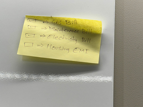 Stock photo showing close-up view of whiteboard with an adhesive note with checklist and checkboxes written in ballpoint pen.