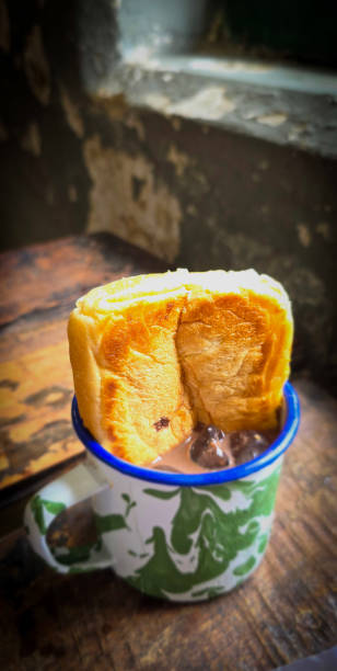 istock Ice chocolate drink on a vintage Indonesian iron mug with random green pattern called Blirik cup or cangkir Blirik on bokeh background along with chocolate filling bread 2148580387